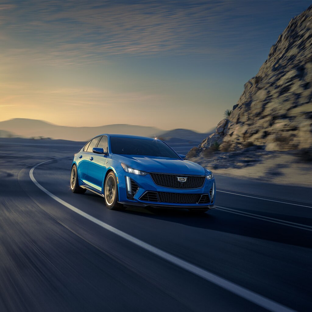 Cadillac CT5 2025 circulando a toda velocidad por una curva en un pintoresco camino montañoso
