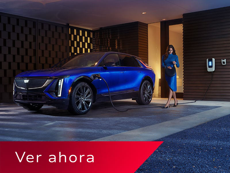 Una mujer con un bolso caminando hacia una Cadillac LYRIQ azul mientras se está cargando en un garaje de lujo