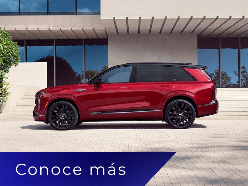 Vista de perfil de una Cadillac VISTIQ en Rojo estacionada en la entrada de una casa moderna con piso de ladrillo Blanco