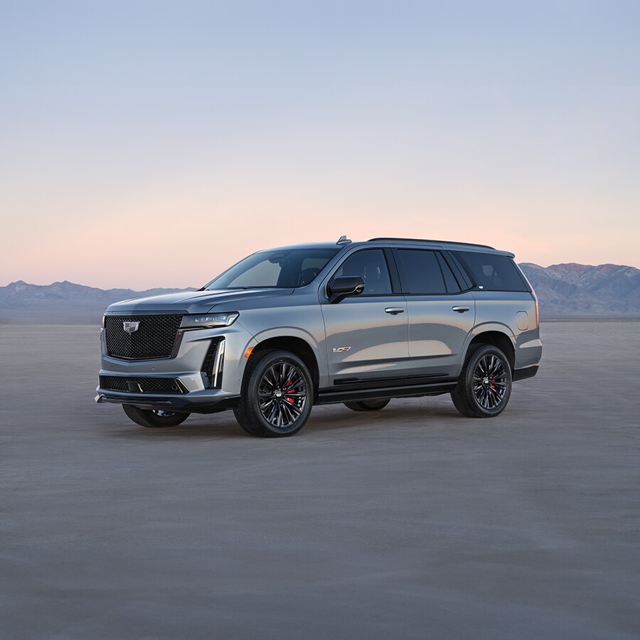 Cadillac Escalade V 2023 estacionada sobre arena, con montañas sobresaliendo al fondo