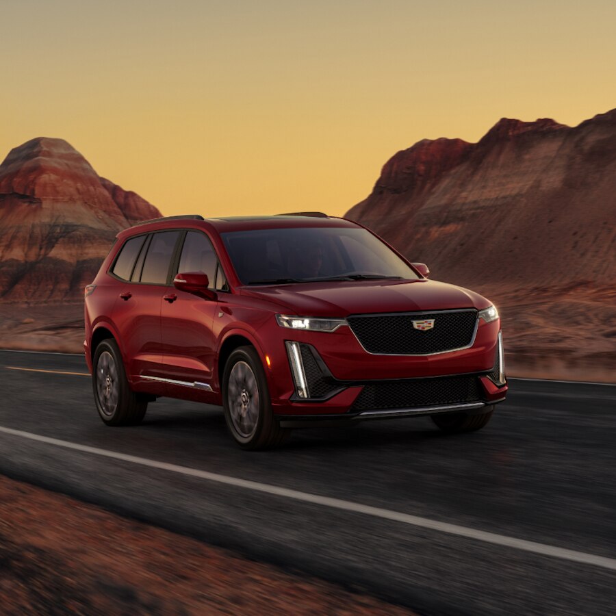 Cadillac XT6 2024 circulando por un camino panorámico, con rocas de color rojo a los costados