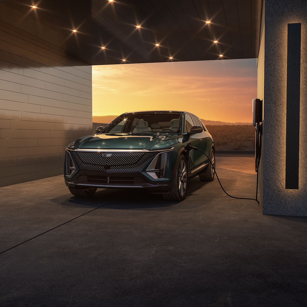 Cadillac LYRIQ estacionada en un garaje mientras carga con un magnífico atardecer de fondo